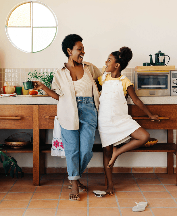 A woman and a girl in a kitchen smiling