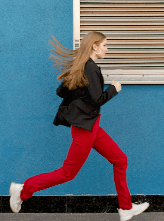 woman in red pants running along side walk