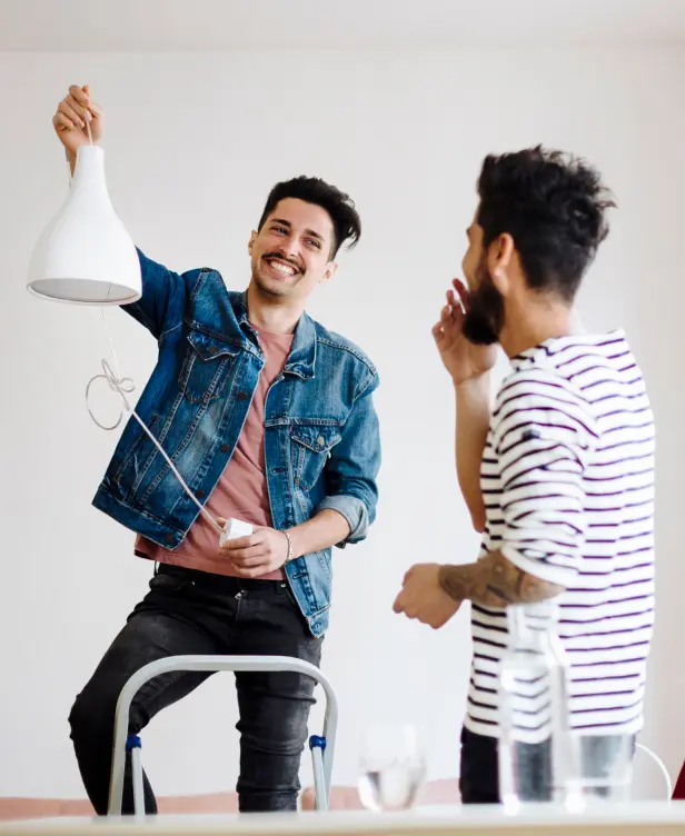 Two men smiling as they hang a light fixture